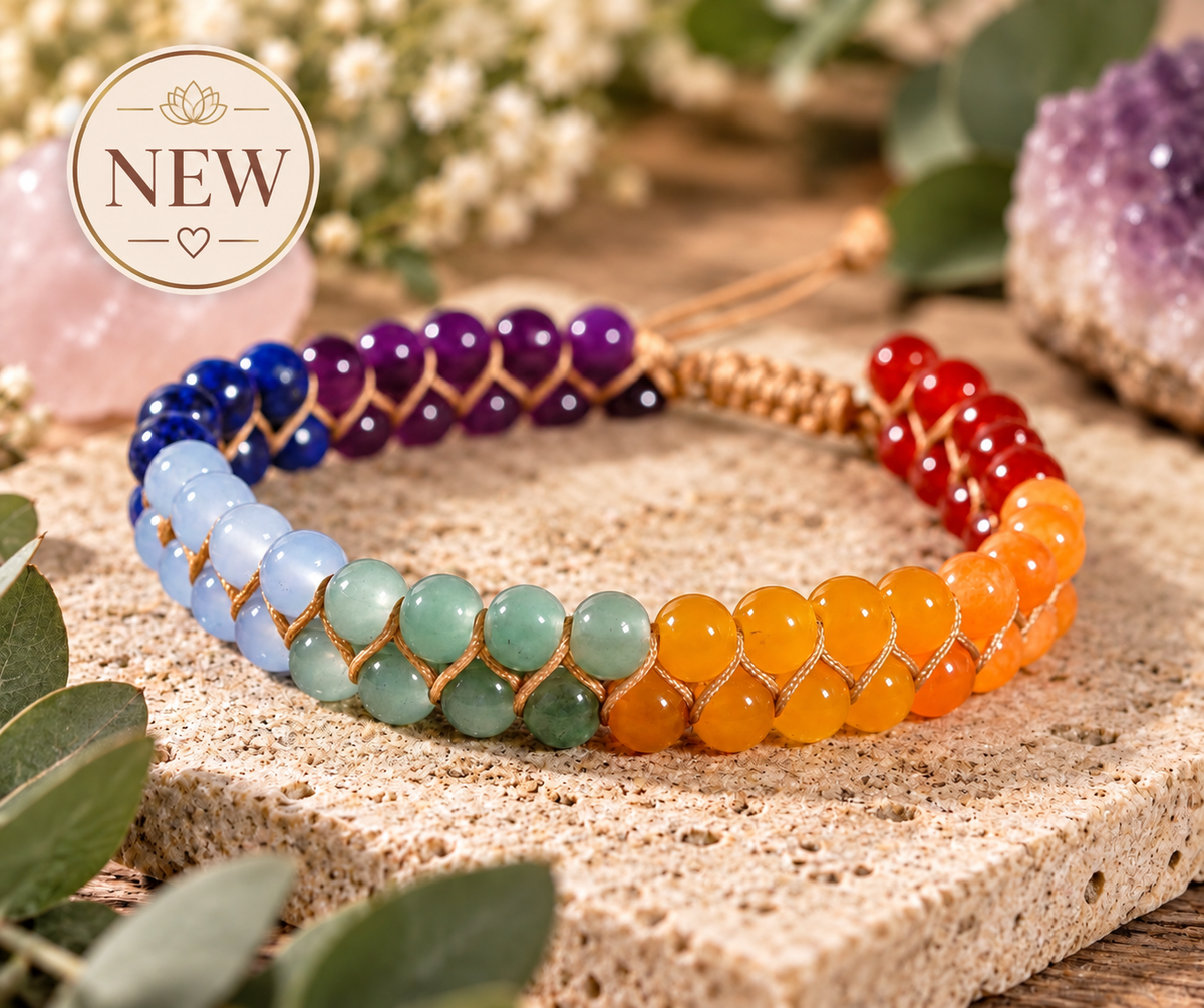 Alt text: Chakra-inspired rainbow beaded bracelet by ALIA, displayed on natural stone with eucalyptus, rose quartz and amethyst, featuring a NEW badge.